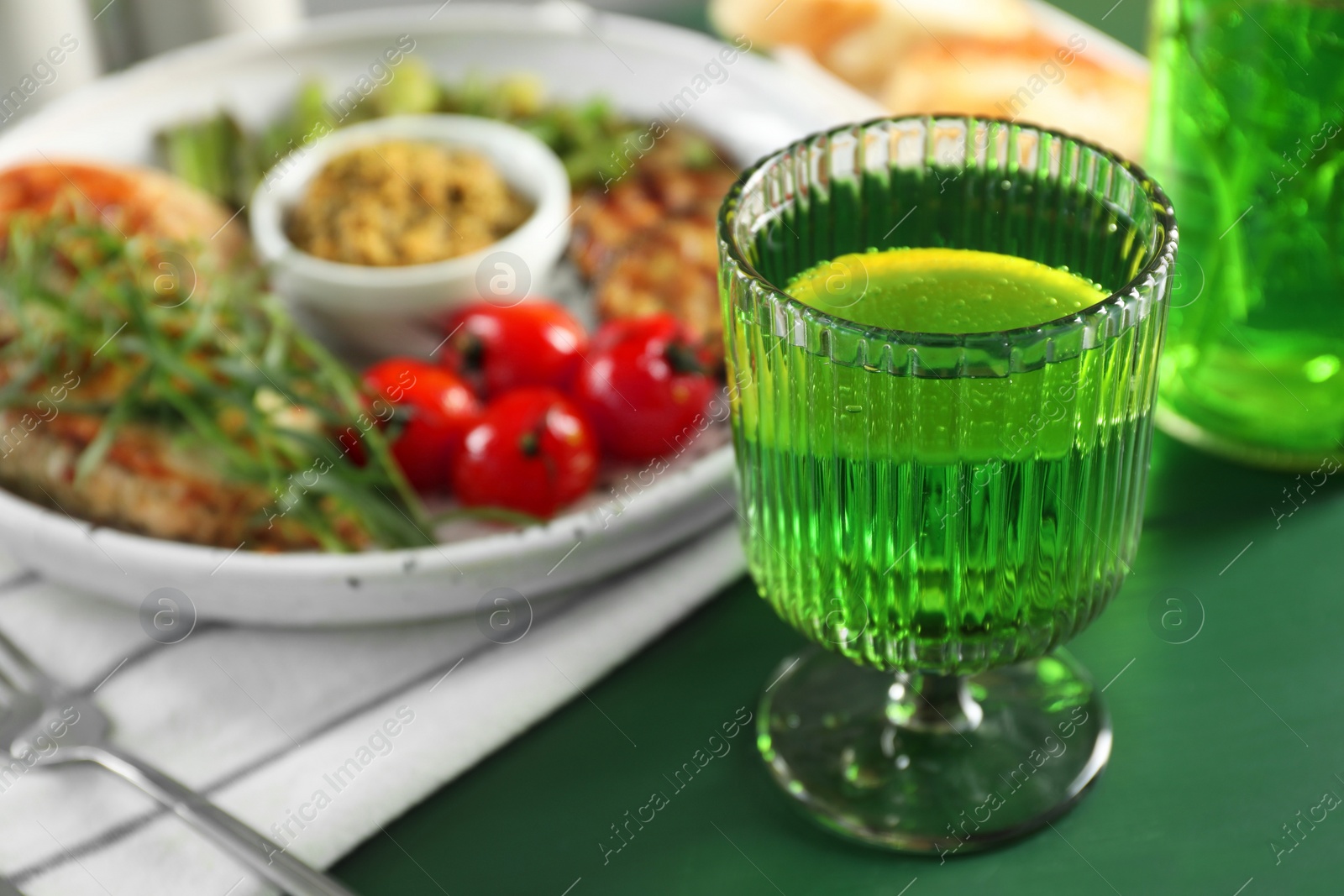 Photo of Delicious drink with tarragon in glass on green table, closeup. Space for text