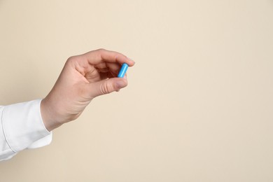 Photo of Woman with pill on beige background, closeup. Space for text