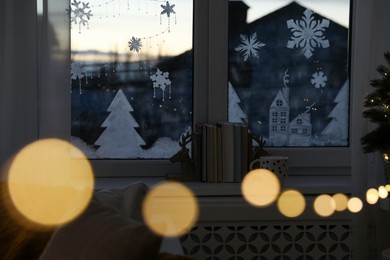 Photo of Books and cup of hot drink near window with beautiful drawing at home. Christmas decor
