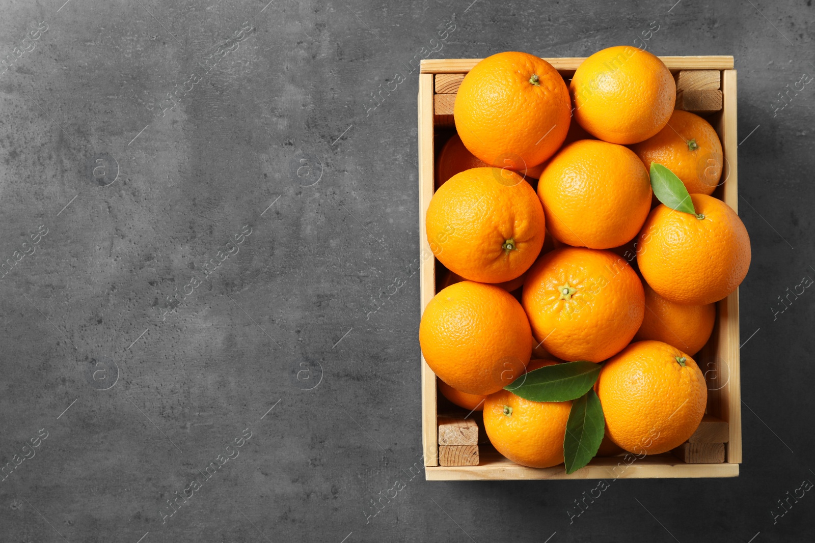 Photo of Wooden crate with ripe oranges on grey background, top view. Space for text