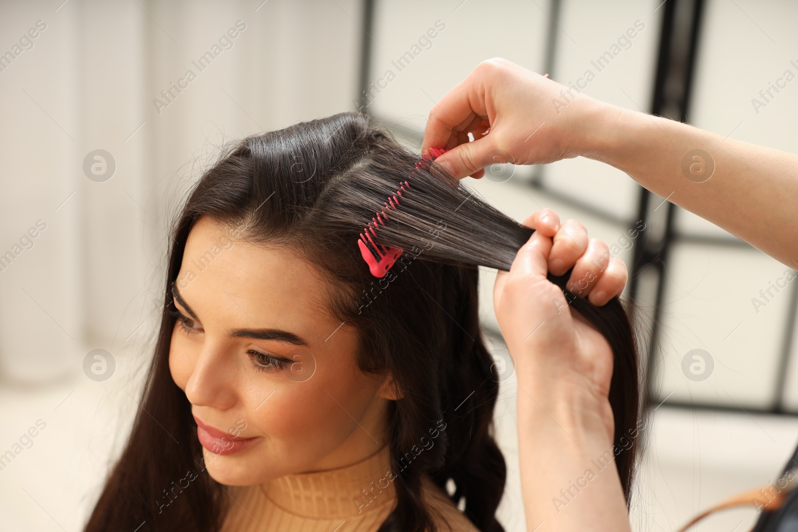 Photo of Hair styling. Professional hairdresser combing woman's hair indoors, closeup