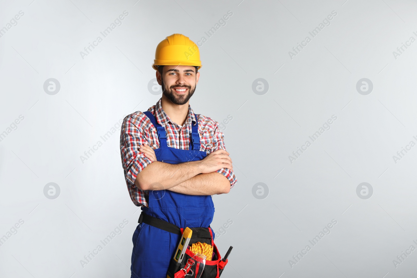 Photo of Portrait of construction worker with tool belt on light background. Space for text