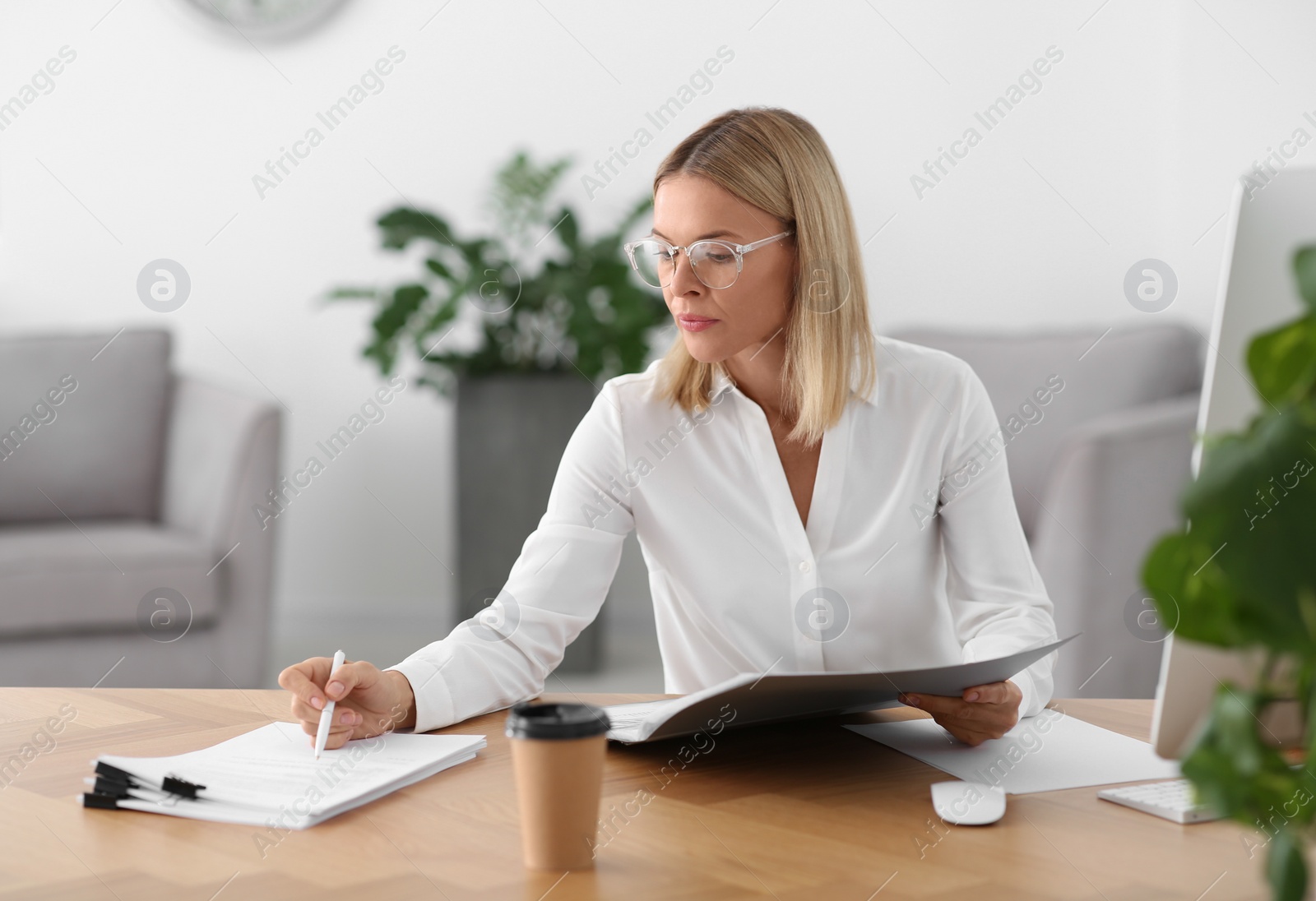 Photo of Woman working with documents at wooden table in office