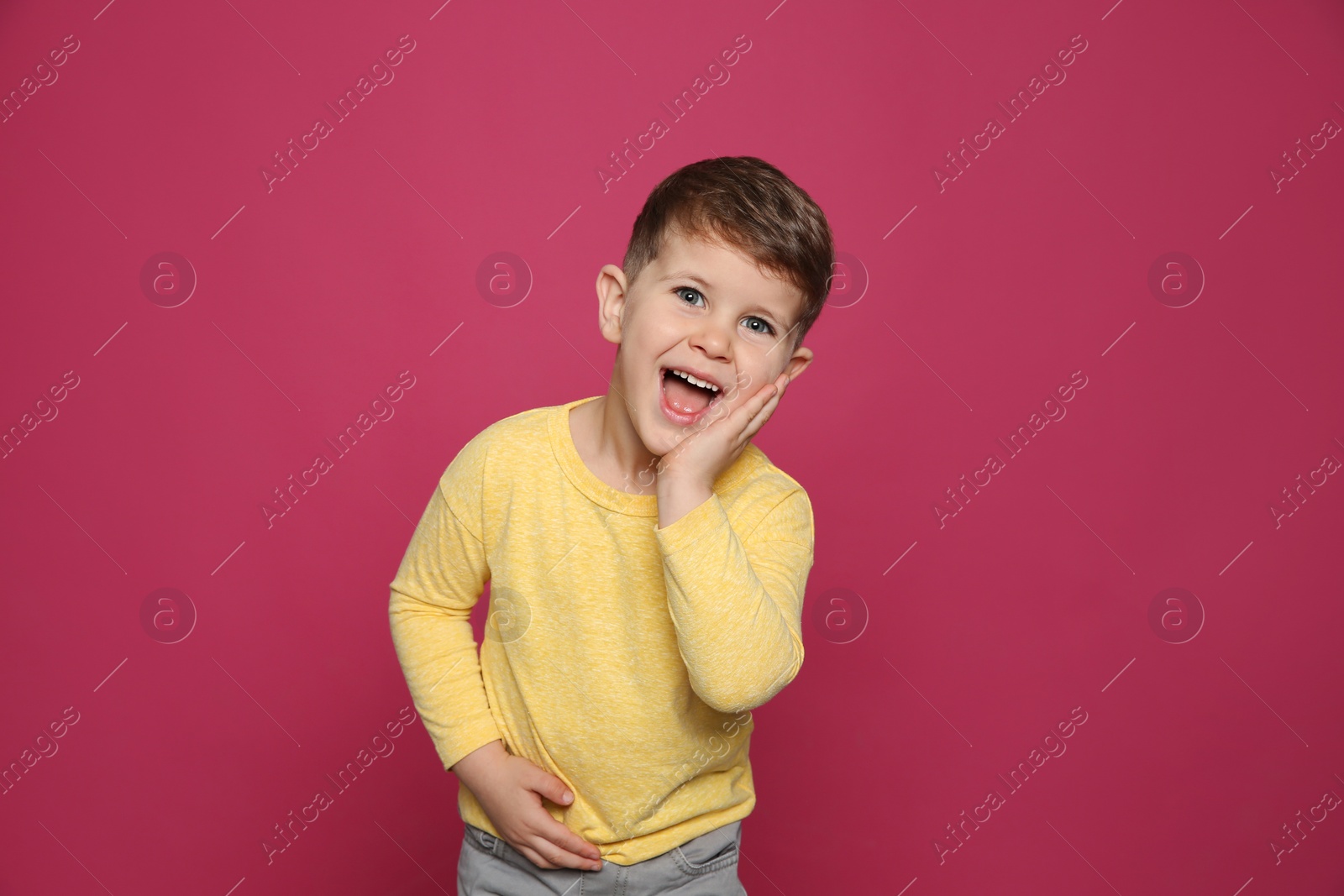 Photo of Portrait of little boy laughing on color background