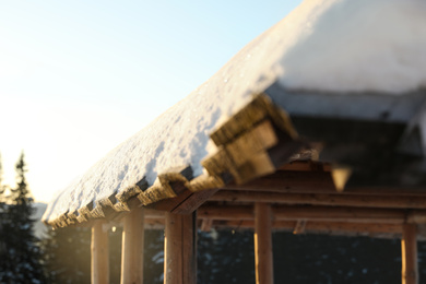 Photo of Wooden gazebo near snowy coniferous forest, closeup. Winter vacation