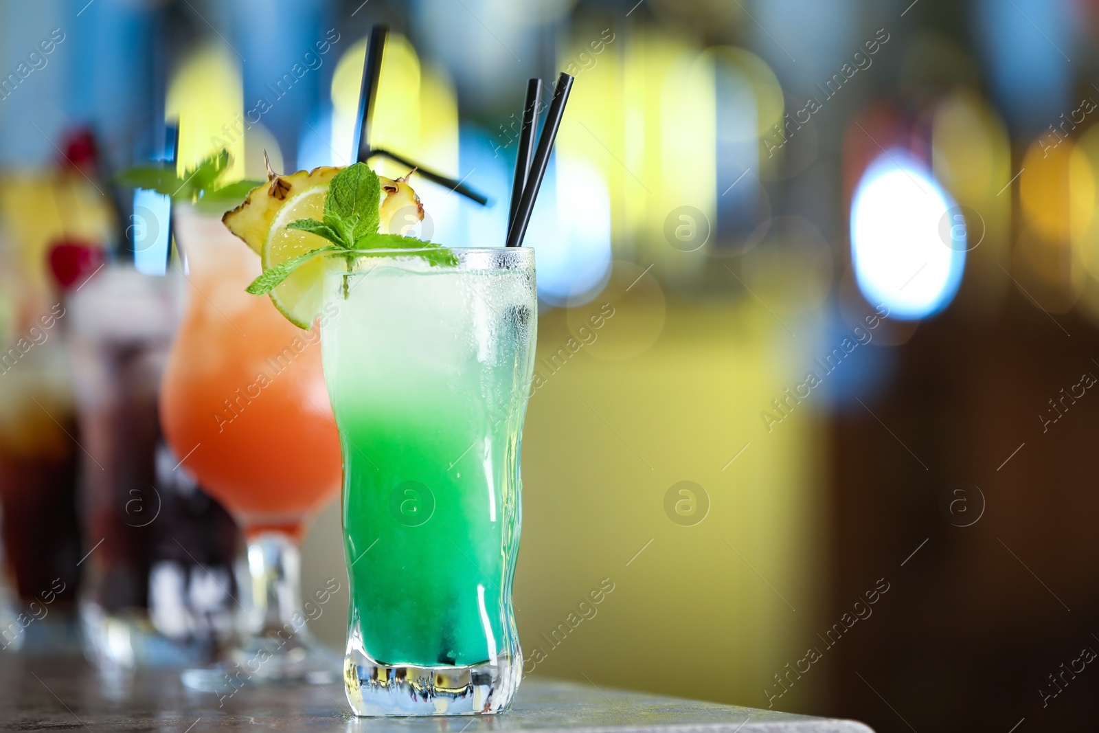 Photo of Row of different fresh alcoholic cocktails on bar counter