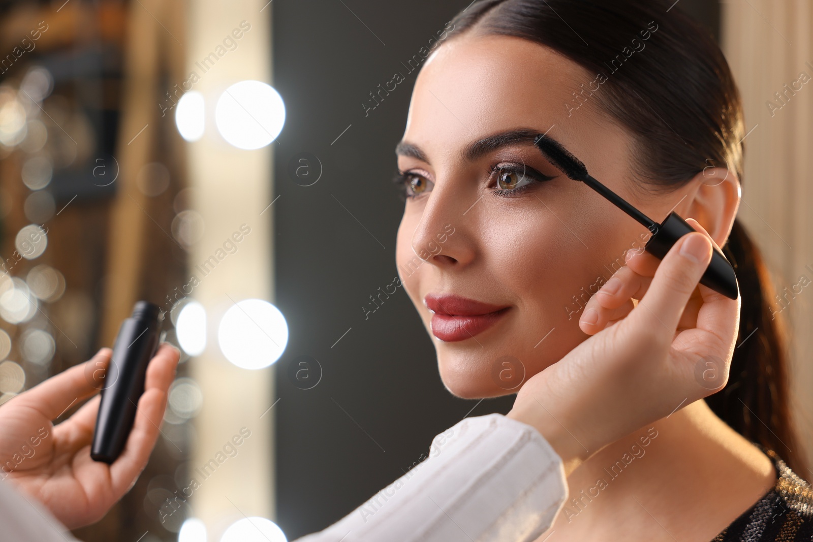 Photo of Makeup artist working with beautiful woman in dressing room, closeup