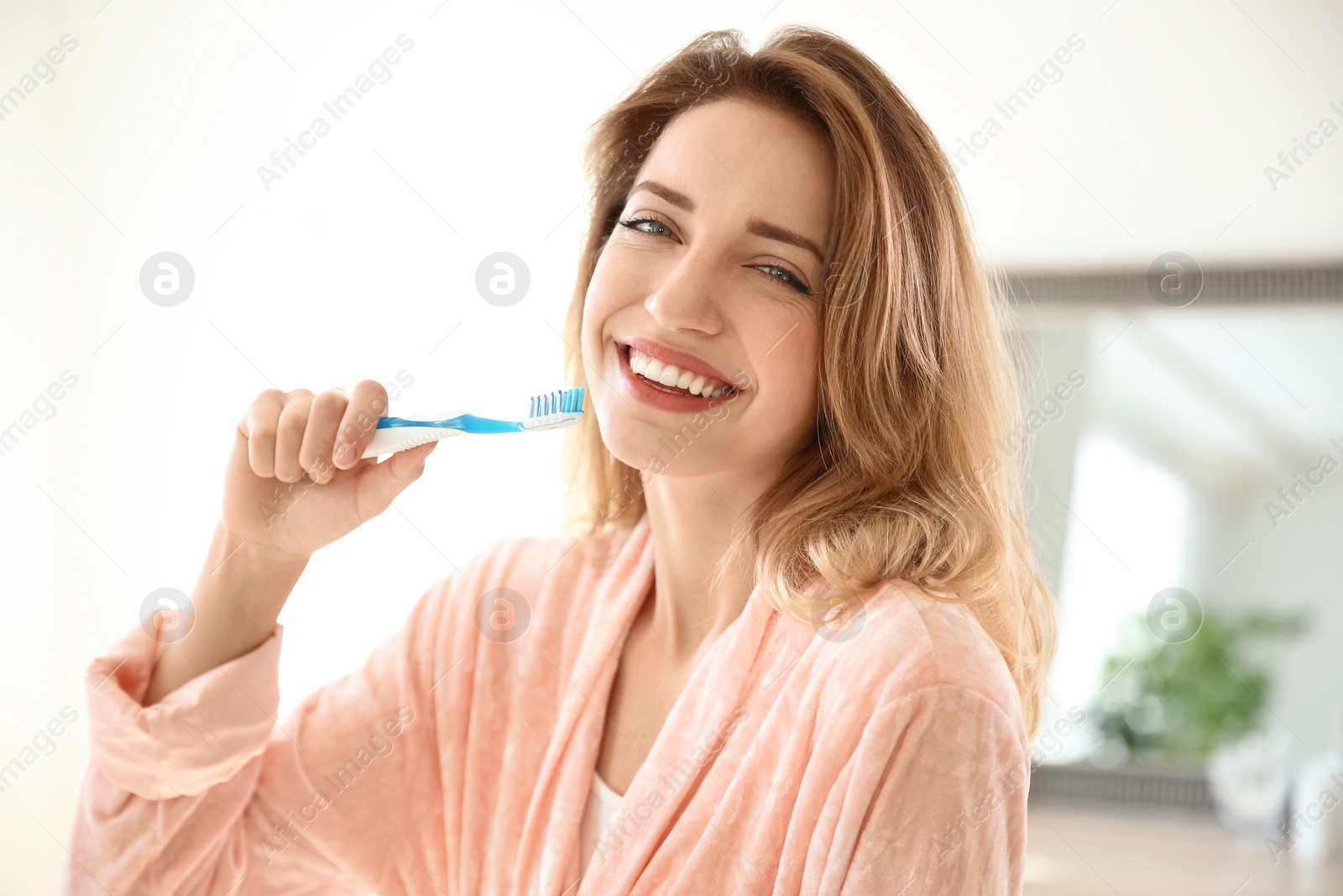 Photo of Portrait of young woman with toothbrush in bathroom. Personal hygiene