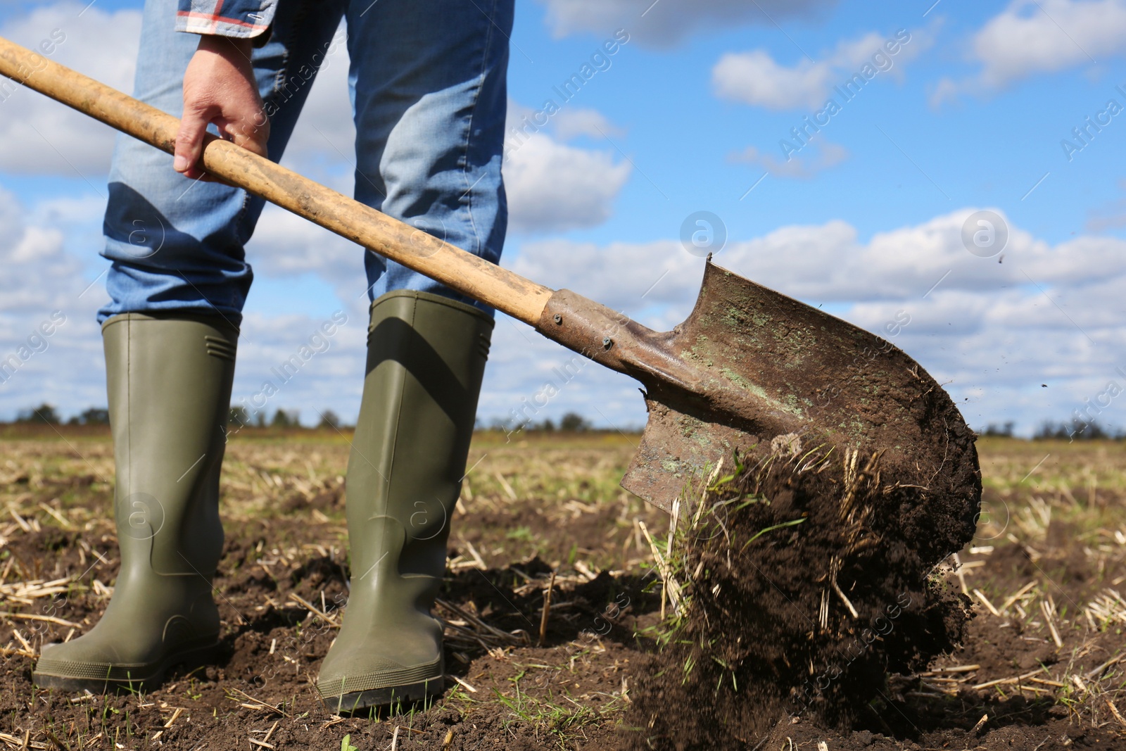 Photo of Man digging soil with shovel in field, closeup