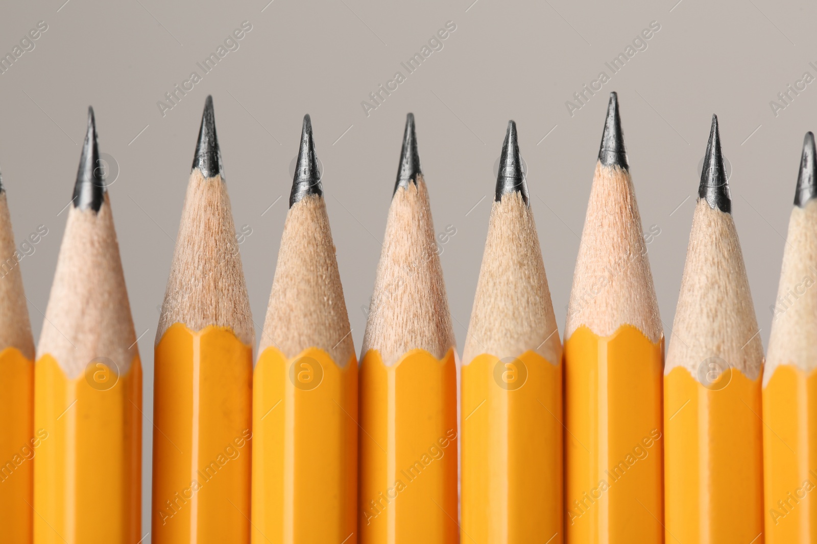 Photo of Many sharp graphite pencils on grey background, macro view