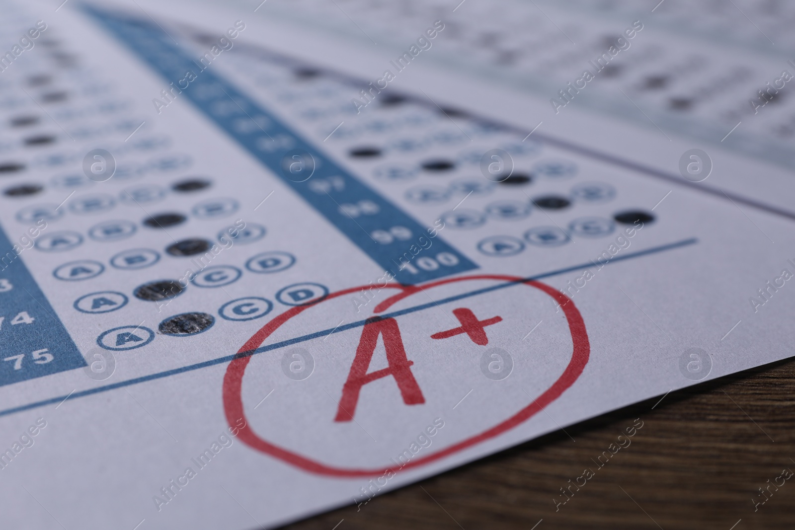 Photo of School grade. Answer sheet with red letter A and plus symbol on wooden table, closeup