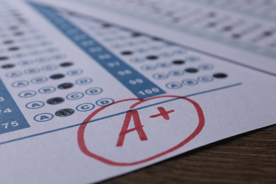 School grade. Answer sheet with red letter A and plus symbol on wooden table, closeup