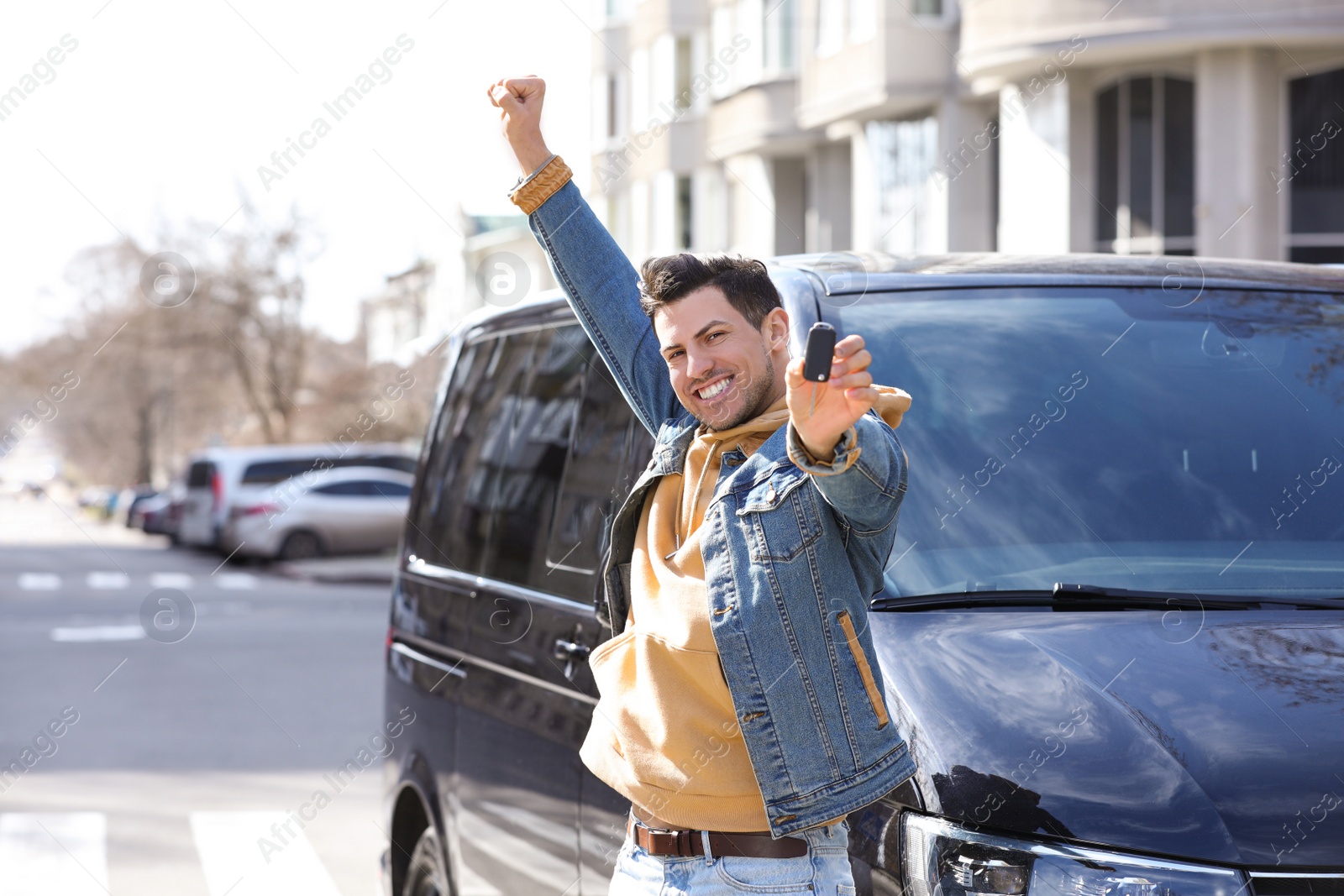 Photo of Man with key near car on city street. Buying new auto