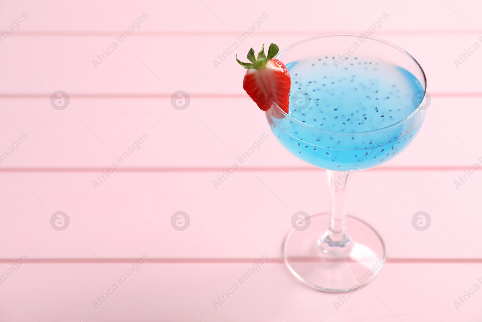 Photo of Tasty light blue cocktail on pink wooden table, space for text