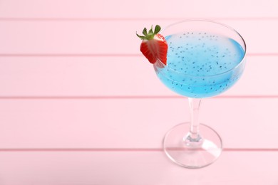 Photo of Tasty light blue cocktail on pink wooden table, space for text