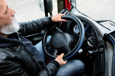 Mature driver sitting in cab of modern truck, closeup view