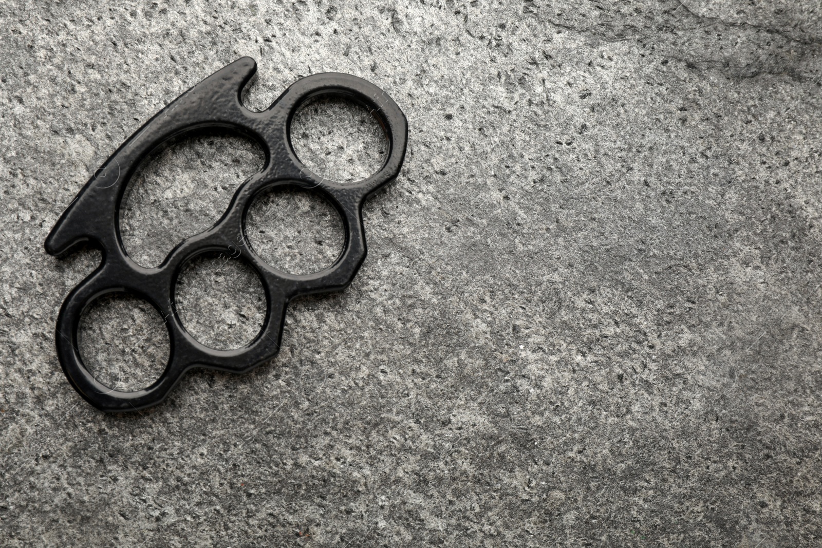 Photo of Black brass knuckles on grey background, top view. Space for text