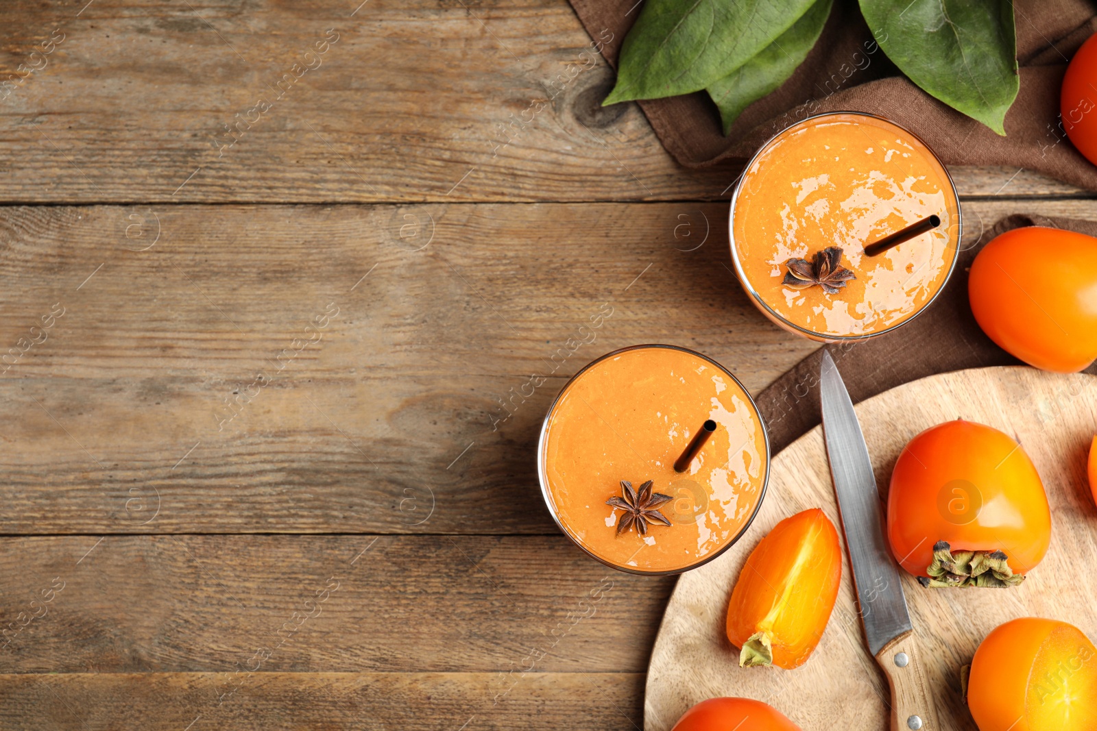 Photo of Tasty persimmon smoothie with anise and fresh fruits on wooden table, flat lay. Space for text