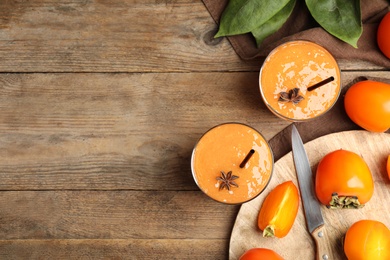 Photo of Tasty persimmon smoothie with anise and fresh fruits on wooden table, flat lay. Space for text