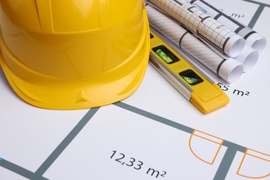 Construction drawings, safety hat and bubble level on house plan, closeup