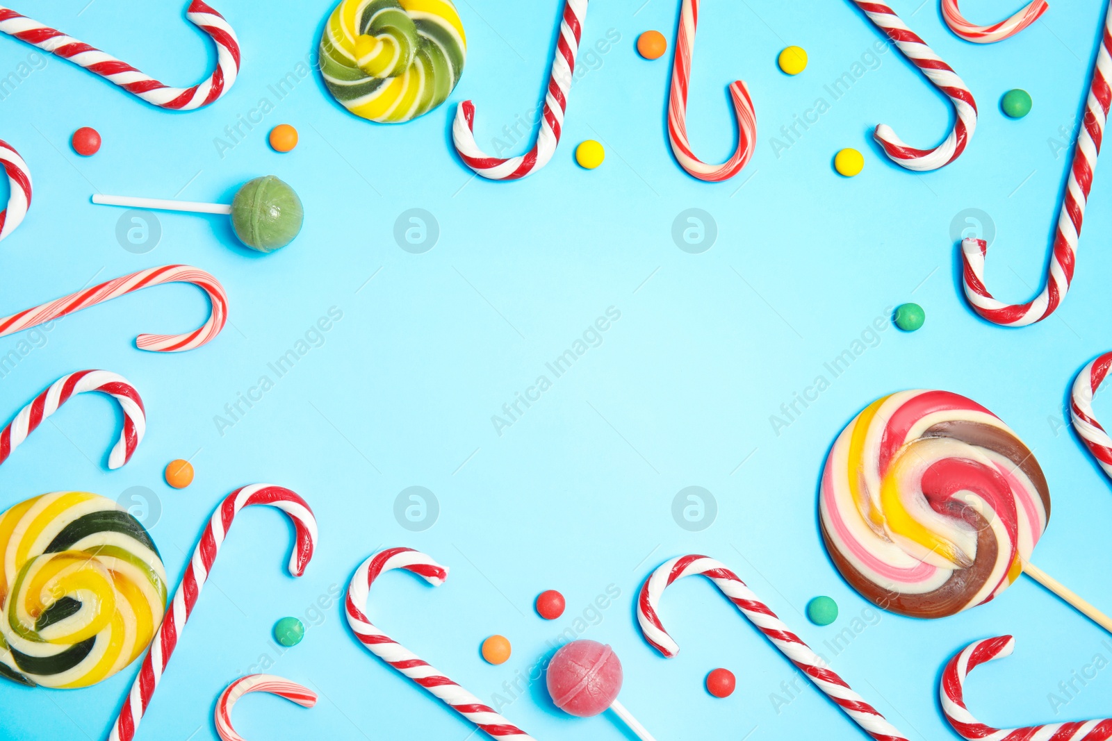 Photo of Flat lay composition with tasty candy canes and space for text on color background