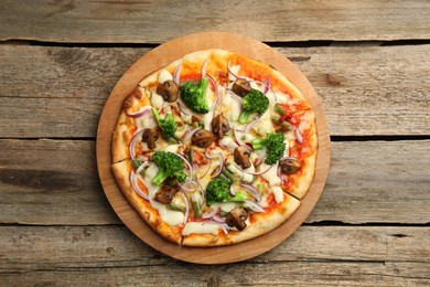 Photo of Board with delicious vegetarian pizza on wooden table, top view