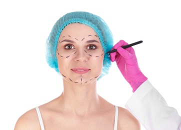 Doctor drawing marks on woman's face against white background. Cosmetic surgery