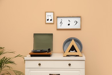 Vinyl records and player on white wooden drawer dresser near beige wall