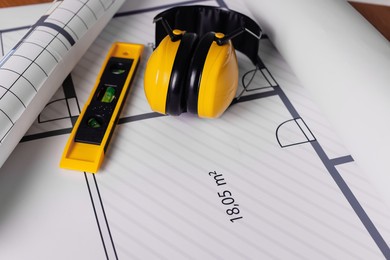 Photo of Construction drawings, safety headphones and ruler, closeup view