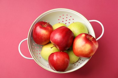 Photo of Colander with fresh apples on pink table, top view