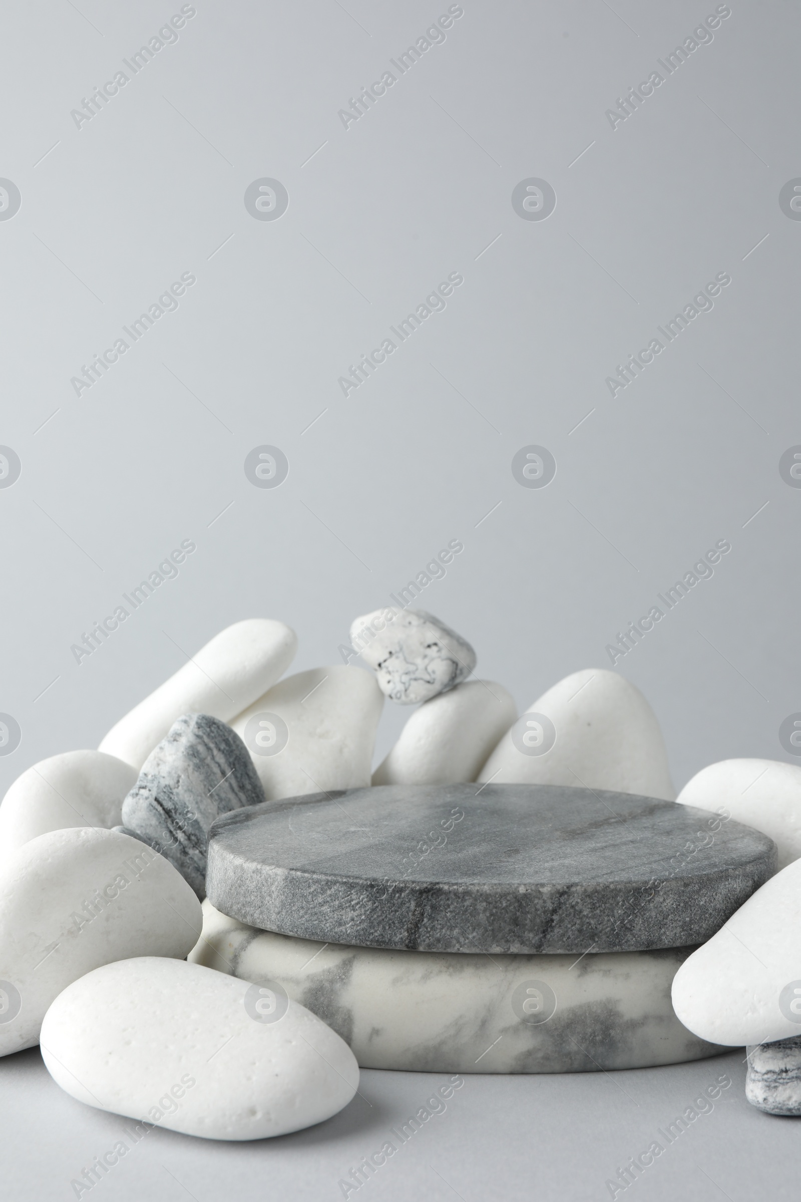 Photo of Presentation for product. Stone podium and pebbles on light grey background. Space for text