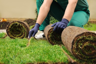 Photo of Worker unrolling grass sods at backyard, closeup