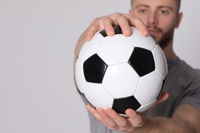 Photo of Athletic young man with soccer ball on light grey background, selective focus. Space for text