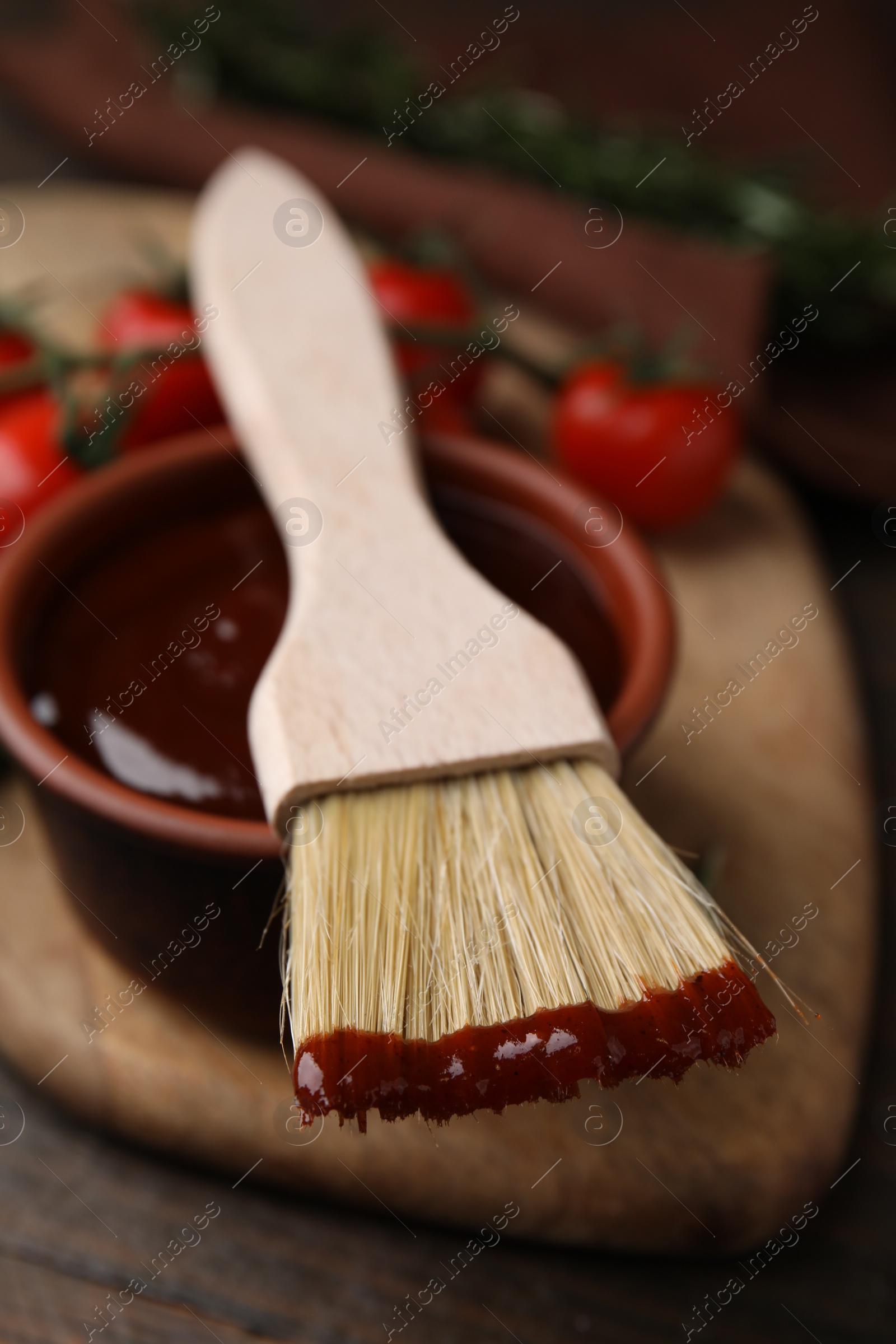 Photo of Marinade in bowl and basting brush on table, closeup