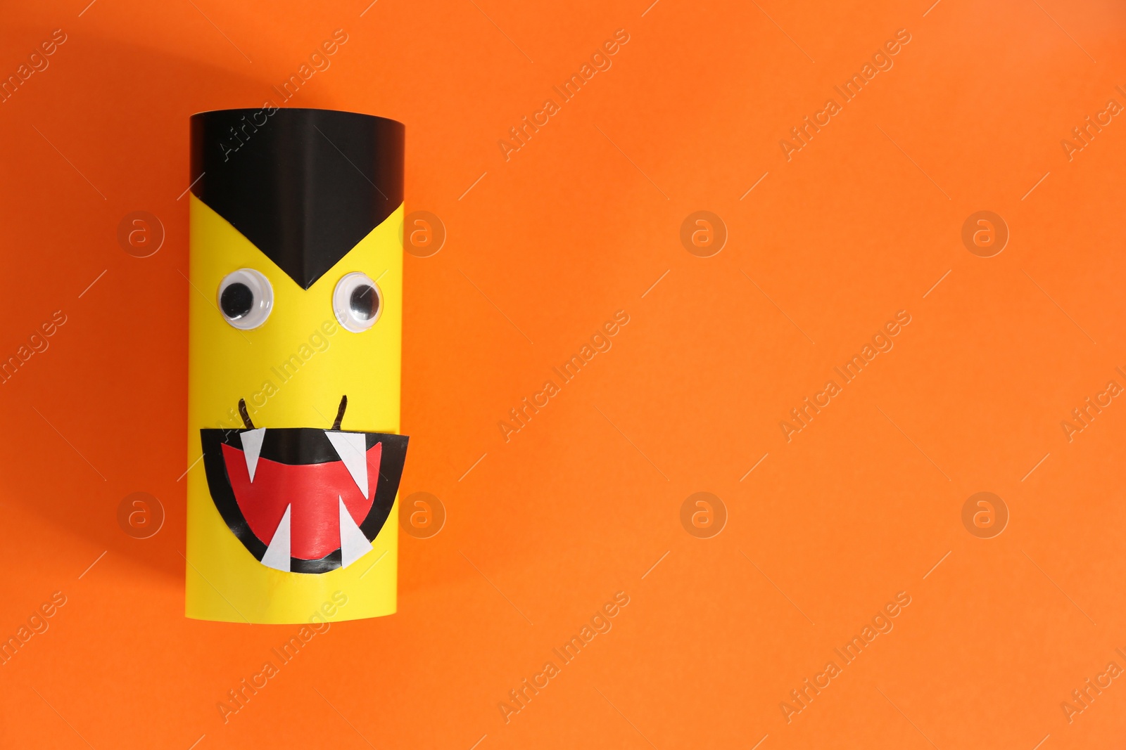 Photo of Funny yellow monster on orange background, top view with space for text. Halloween decoration