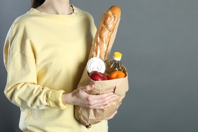 Humanitarian aid. Woman with food products for donation on grey background, closeup
