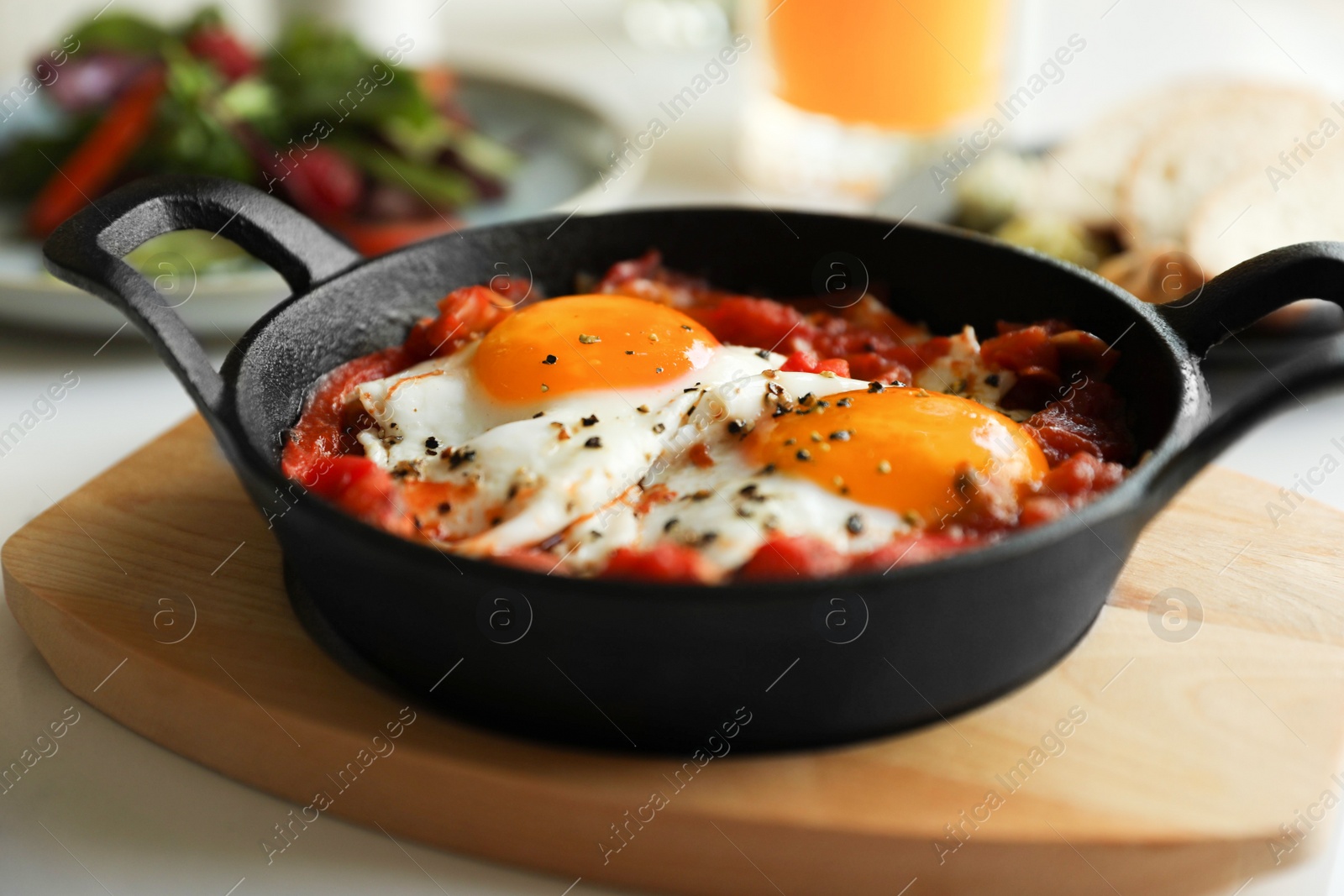 Photo of Tasty Shakshouka served in pan on table, closeup