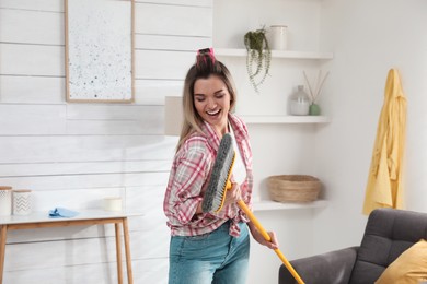 Photo of Woman with mop singing while cleaning at home