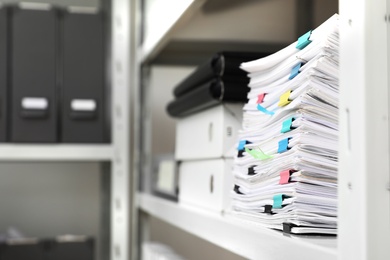 Photo of Stack of documents with paper clips on shelf in office. Space for text