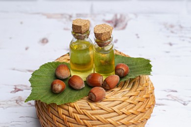Photo of Bottles of hazelnut essential oil and nuts on table