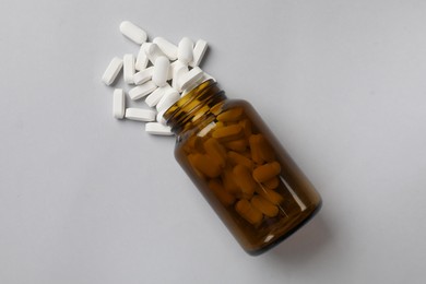 Vitamin pills and bottle on light grey background, top view