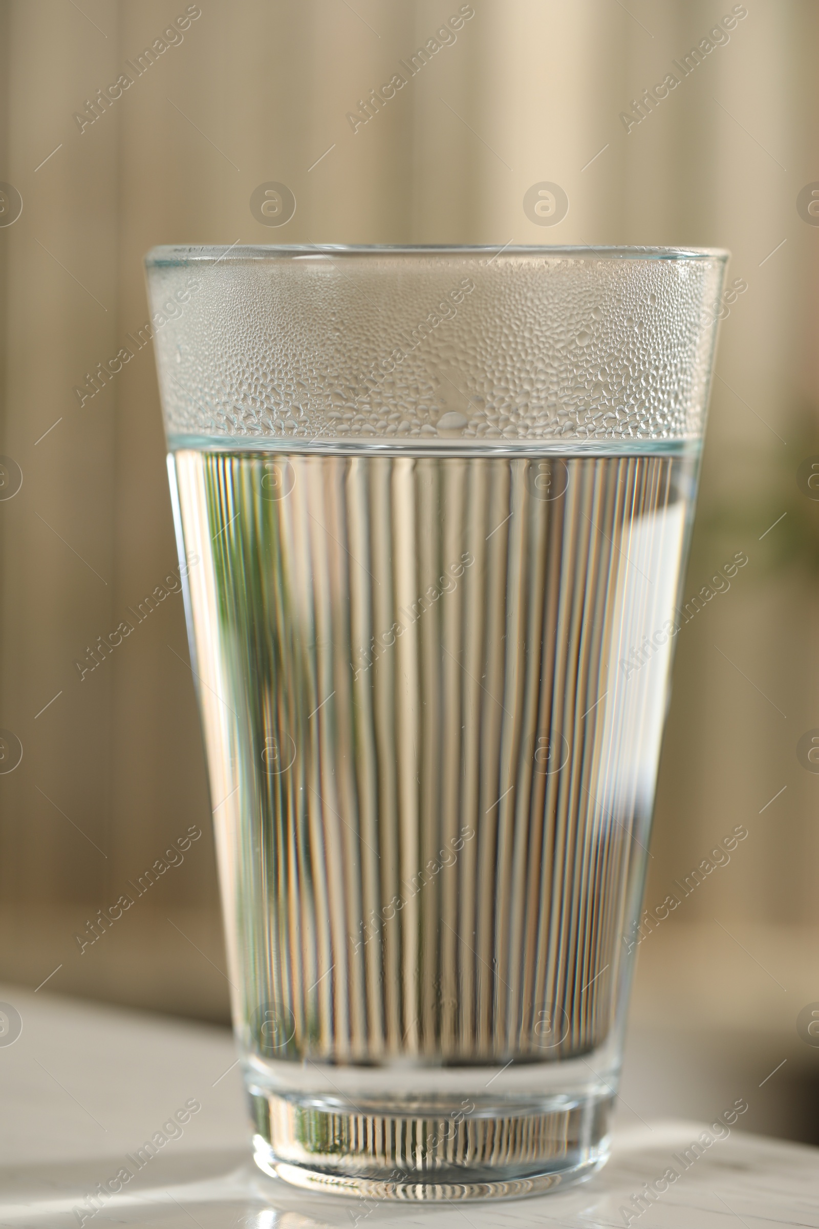 Photo of Glass of pure water on white table against blurred background, closeup