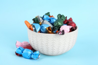 Photo of Candies in colorful wrappers on light blue background, closeup