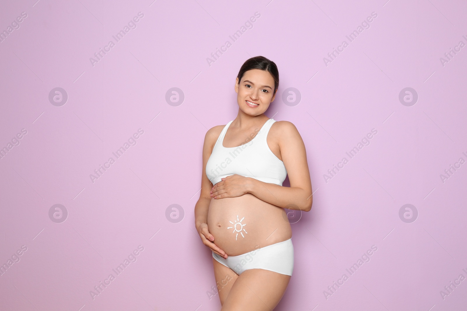 Photo of Sun painted with body cream on pregnant woman's belly against color background