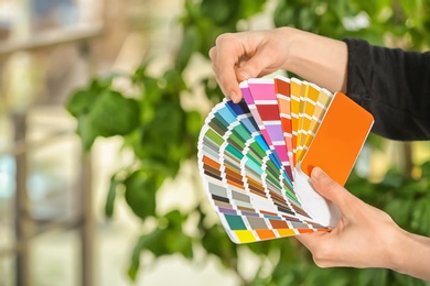 Photo of Female designer holding color palette samples on blurred background