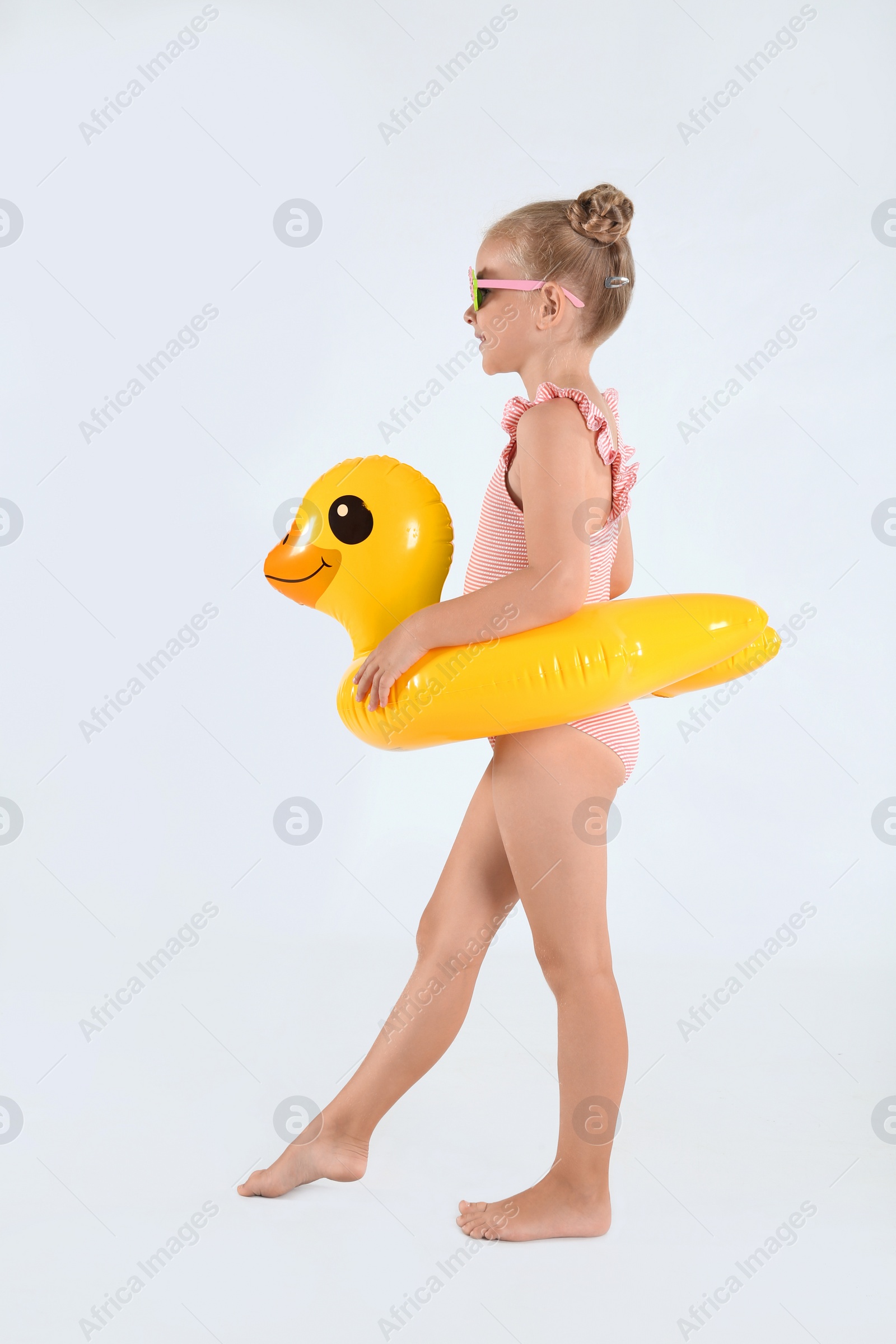 Photo of Cute little child in beachwear with bright inflatable ring on white background