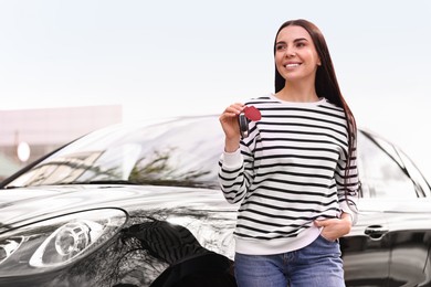 Photo of Woman holding car flip key near her vehicle outdoors