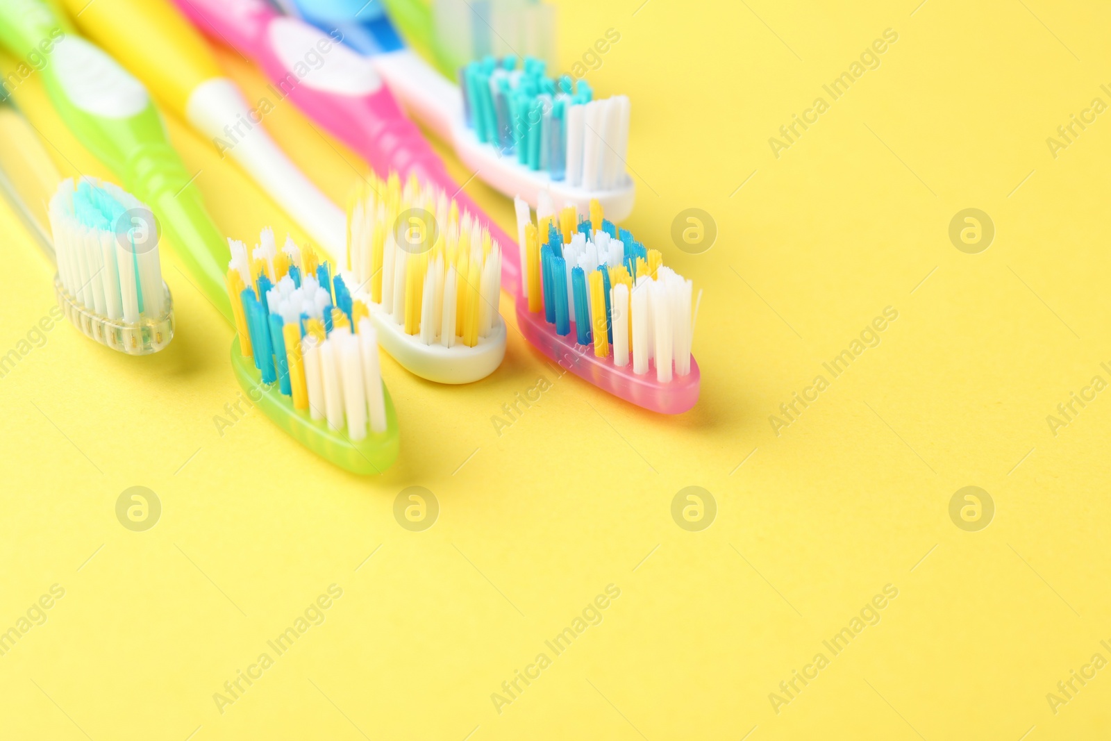 Photo of Different toothbrushes on yellow background, closeup. Space for text