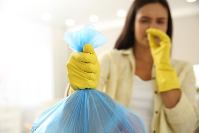 Photo of Woman holding full garbage bag at home, focus on hand