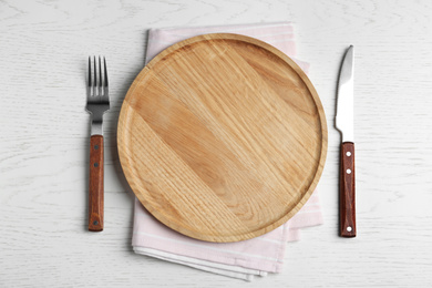 Photo of Empty wooden serving board with cutlery and napkin on white table, flat lay